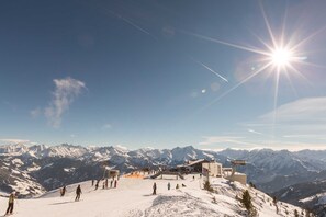 A ski resort with a chairlift, snow-covered mountains, and a clear sky.