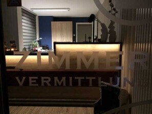 Ein Empfangsschalter mit einem Schild, auf dem 'ZIMMER VERMITTUN' steht.