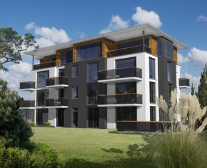 Un immeuble moderne à plusieurs étages, doté de balcons, de grandes fenêtres et d’une pelouse bien entretenue.