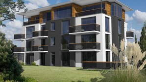 Un immeuble moderne à plusieurs étages, doté de balcons, de grandes fenêtres et d’une pelouse bien entretenue.