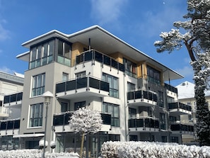 Un immeuble moderne à plusieurs étages, doté de balcons, de grandes fenêtres et d’un toit plat.