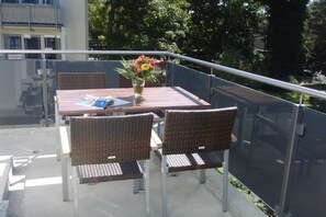 Un balcon avec une table, des chaises et un vase de fleurs.