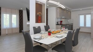 Ein moderner Essbereich mit einem weißen Tisch, gedeckt für sechs Personen, umgeben von schwarzen Stühlen.