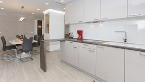 Eine moderne Küche mit weißen Schränken, einer Holzauskładung und einer roten Kaffeemaschine.