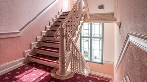 A grand staircase with ornate railings and a patterned carpet leading to a landing.