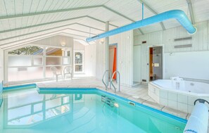 Une piscine intérieure offrant une vue dégagée sur la pièce adjacente, un jacuzzi et un espace douche.