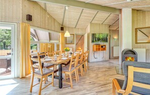 Un espace repas comprenant une longue table en bois et des chaises, une cheminée et un téléviseur fixé au mur.