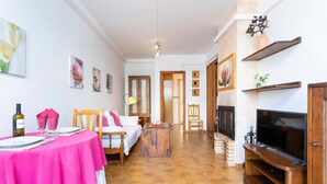 A cozy room with a bed, a dining table with pink tablecloth, a TV, and a fireplace. - Cala Morlanda Palma d Mallorca (Cala Morlanda)