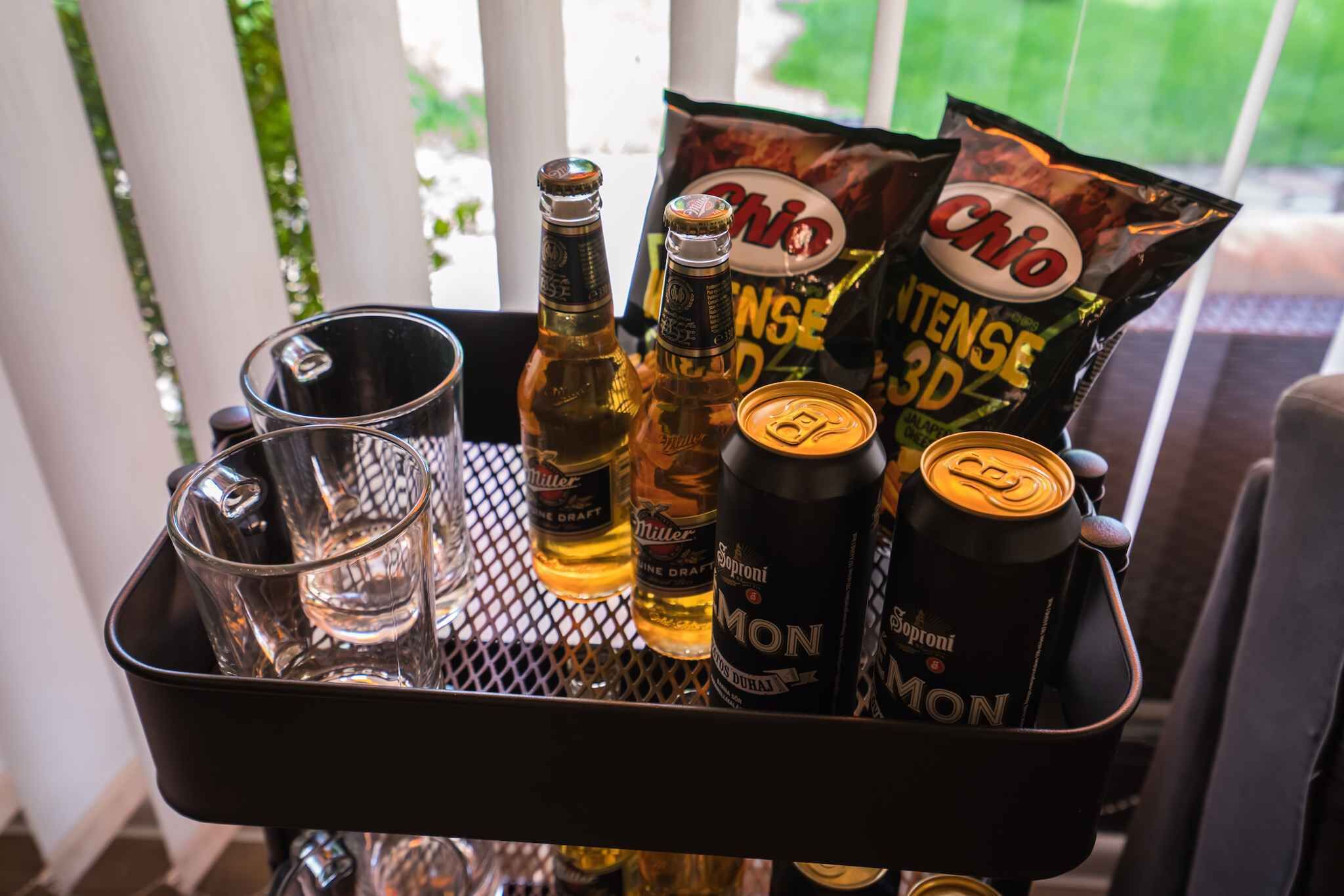A tray with bottles of beer, a can of soda, and bags of chips.