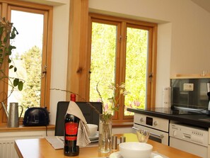 Une cuisine avec une grande fenêtre, une bouteille de vin, une bouilloire et un four Siemens.
