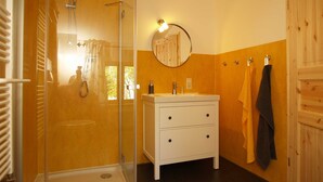 A bathroom with a glass shower enclosure, a white vanity with a mirror, and wooden paneling on the walls. - Pfarrweg 10 PF-10 - PF-10 (Kühlungsborn)