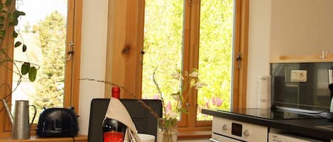 Eine Küche mit großem Fenster, einer Weinflasche, einem Wasserkocher und einem Siemens-Backofen.