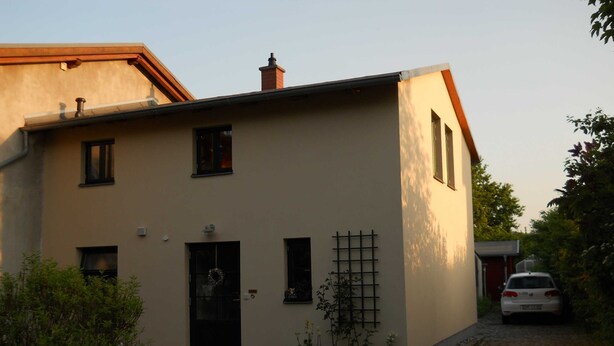 Ein zweistöckiges Haus mit Haustür, einer kleinen Veranda und einem Briefkasten.