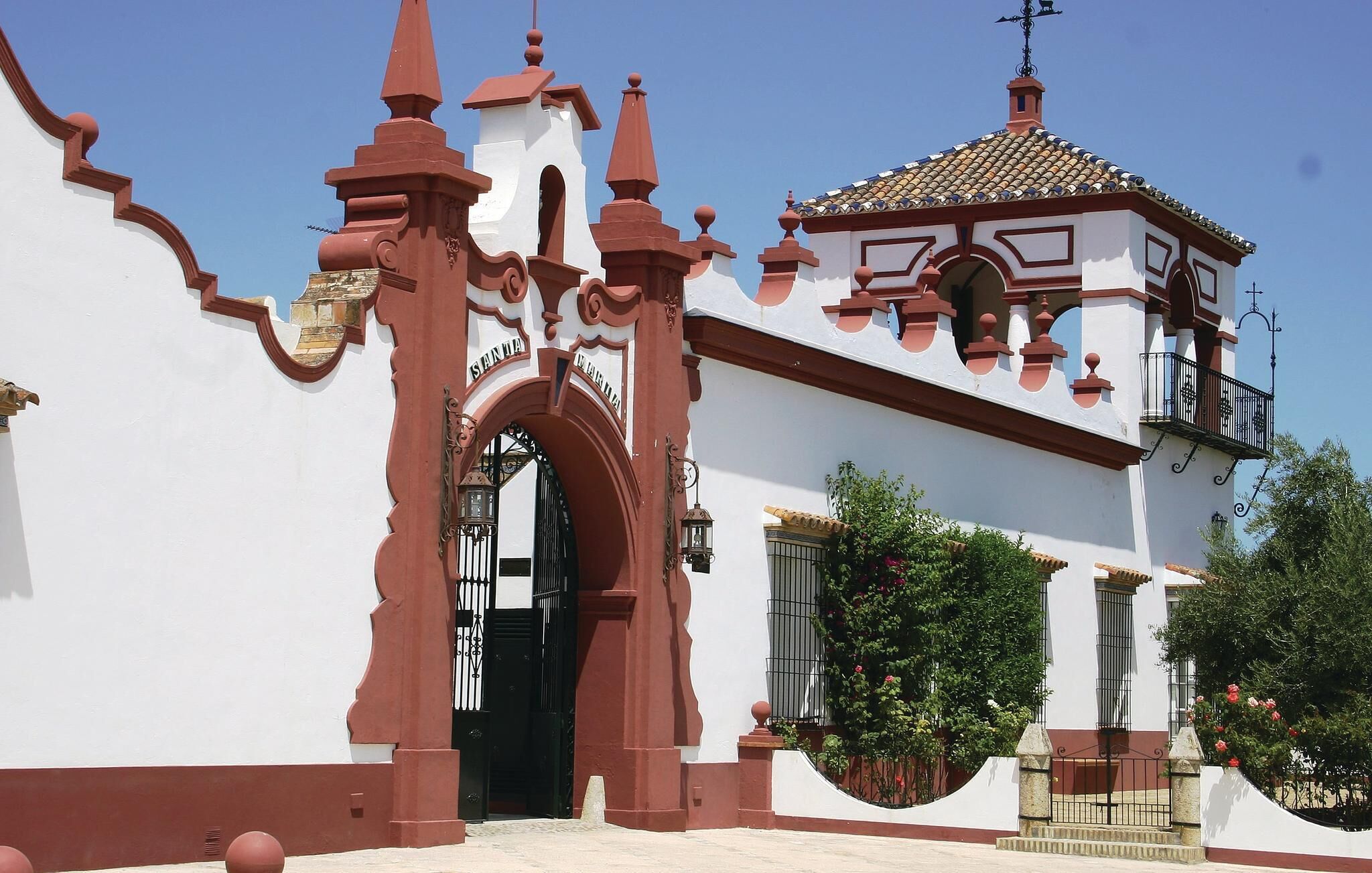 Un bâtiment blanc avec une arche rouge et une petite tour.