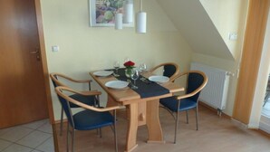 A dining area with a wooden table, four chairs, and a framed picture on the wall. - (225/1) 2-room apartment-Strandstrasse - apartment house Strandburg (Kühlungsborn)