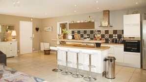 Una cocina moderna con una isla central, taburetes de bar, un refrigerador y un microondas.