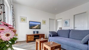 A living room with a grey sofa, wooden coffee table, and a TV on the wall. - Villa Aquamarina Whg.26a, ROOF TERRACE, LAKE VIEW, CHAIR - Villa Aquamarina, 1st floor. (Heringsdorf)