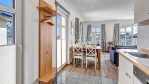 A modern kitchen with a dining area, wooden cabinets, and a view of the city. - Villa Aquamarina Whg.26a, ROOF TERRACE, LAKE VIEW, CHAIR - Villa Aquamarina, 1st floor. (Heringsdorf)