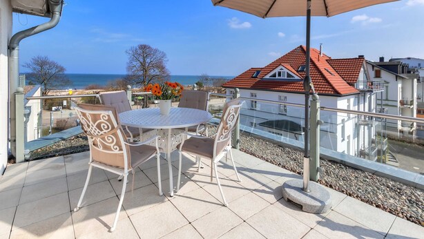 A balcony with a table and chairs, overlooking a body of water and buildings. - Villa Aquamarina Whg.26a, ROOF TERRACE, LAKE VIEW, CHAIR - Villa Aquamarina, 1st floor. (Heringsdorf)