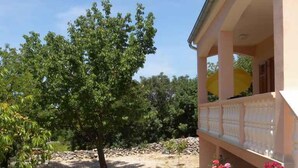 Une maison avec un porche abrité et un jardin agrémenté de fleurs et d’un arbre.