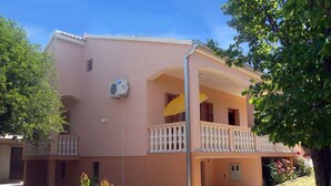 Un bâtiment à deux étages doté d’un balcon, d’un petit jardin et surplombant un ciel dégagé.