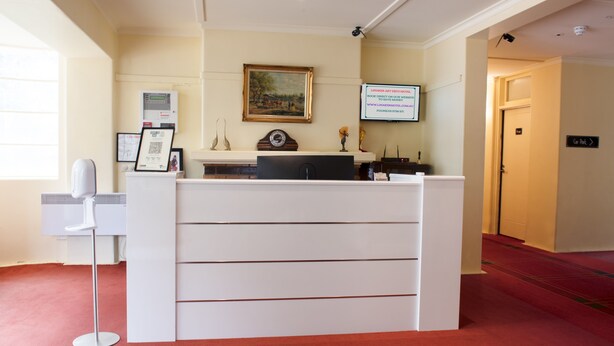 A reception desk with a white counter, a framed picture above it, and a sign on the wall.