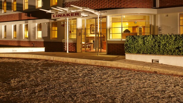 A multi-story hotel with a brick facade, multiple balconies, and a well-lit entrance. - Linaker Art Deco Motel (Beechworth)