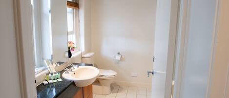 Un baño moderno con lavamanos, inodoro y espejo.