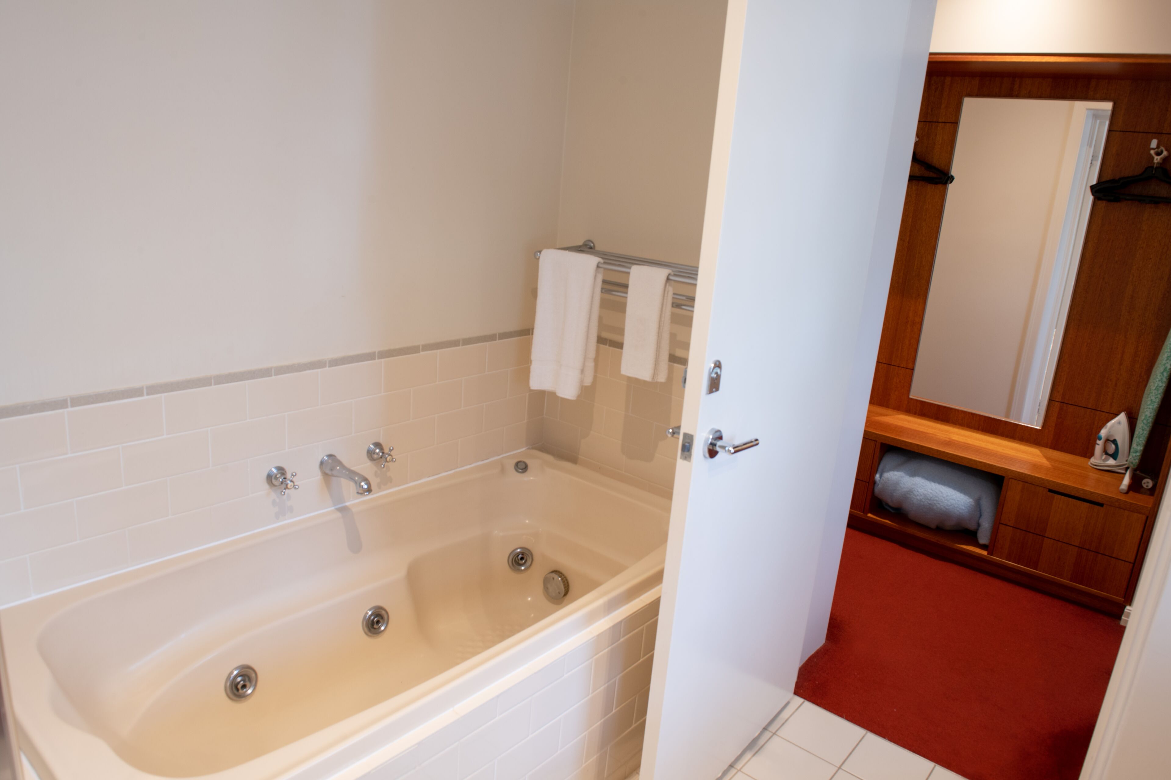A bathroom with a bathtub, a towel rack, and a mirror.