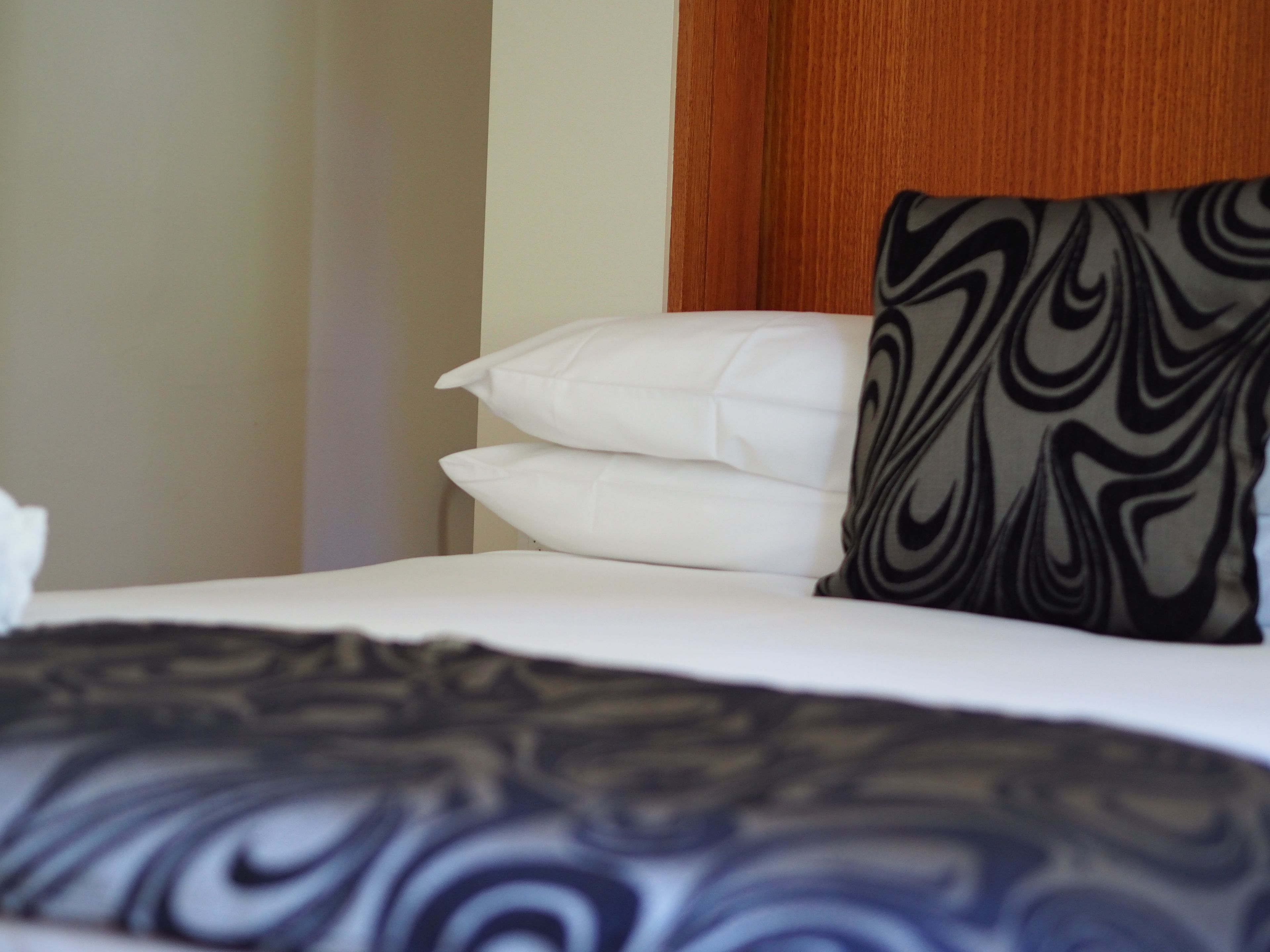 Ein Bett mit weißer Bettwäsche und einem schwarz-weißen Kissen.