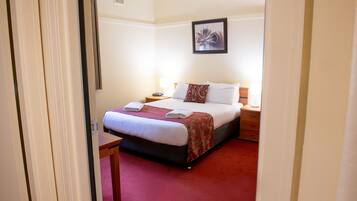 Una habitación de hotel con cama, mesita de noche y mesilla.