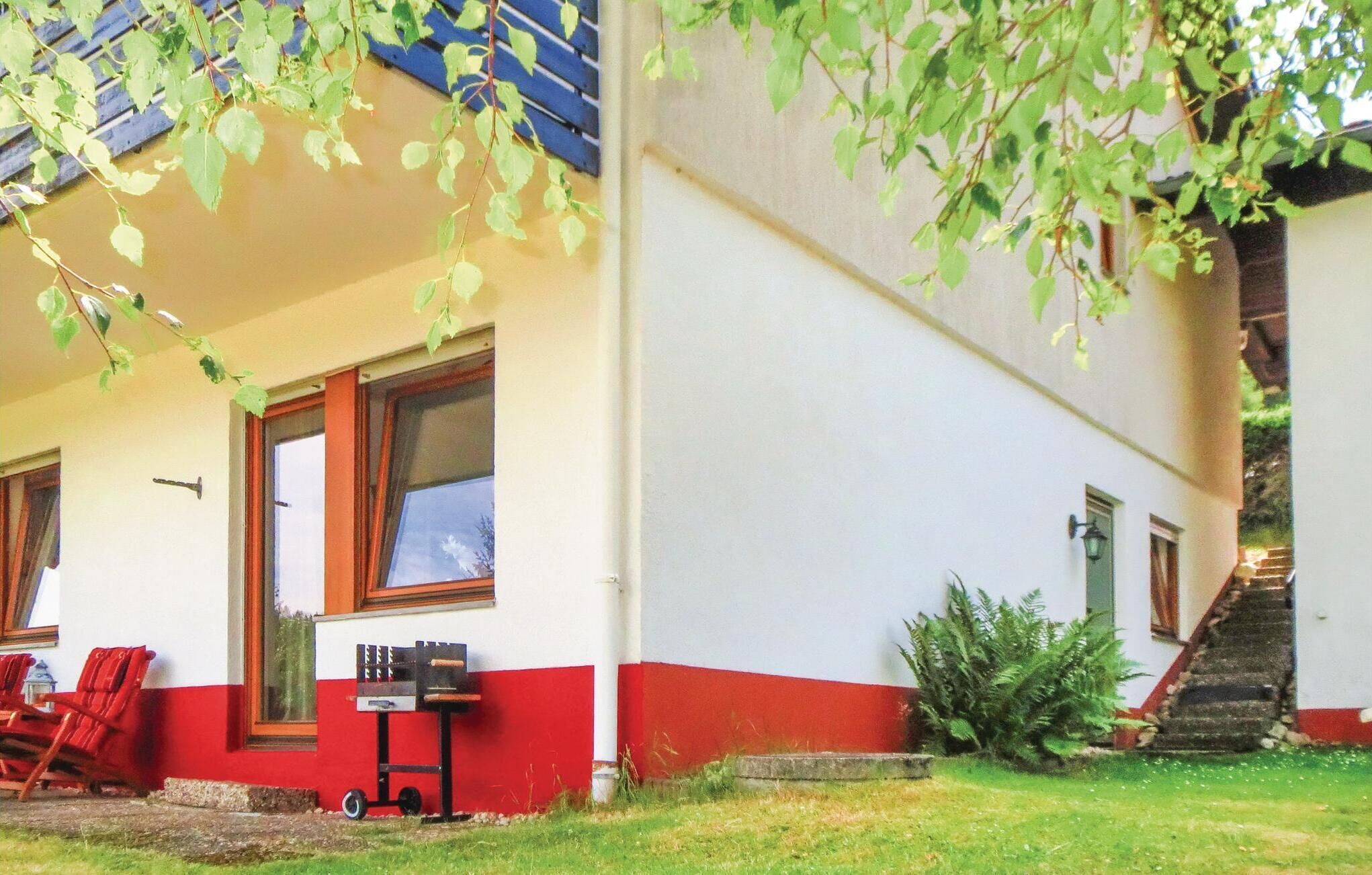 Une maison à l’extérieur rouge et blanc, avec une porte d’entrée et un petit barbecue extérieur.