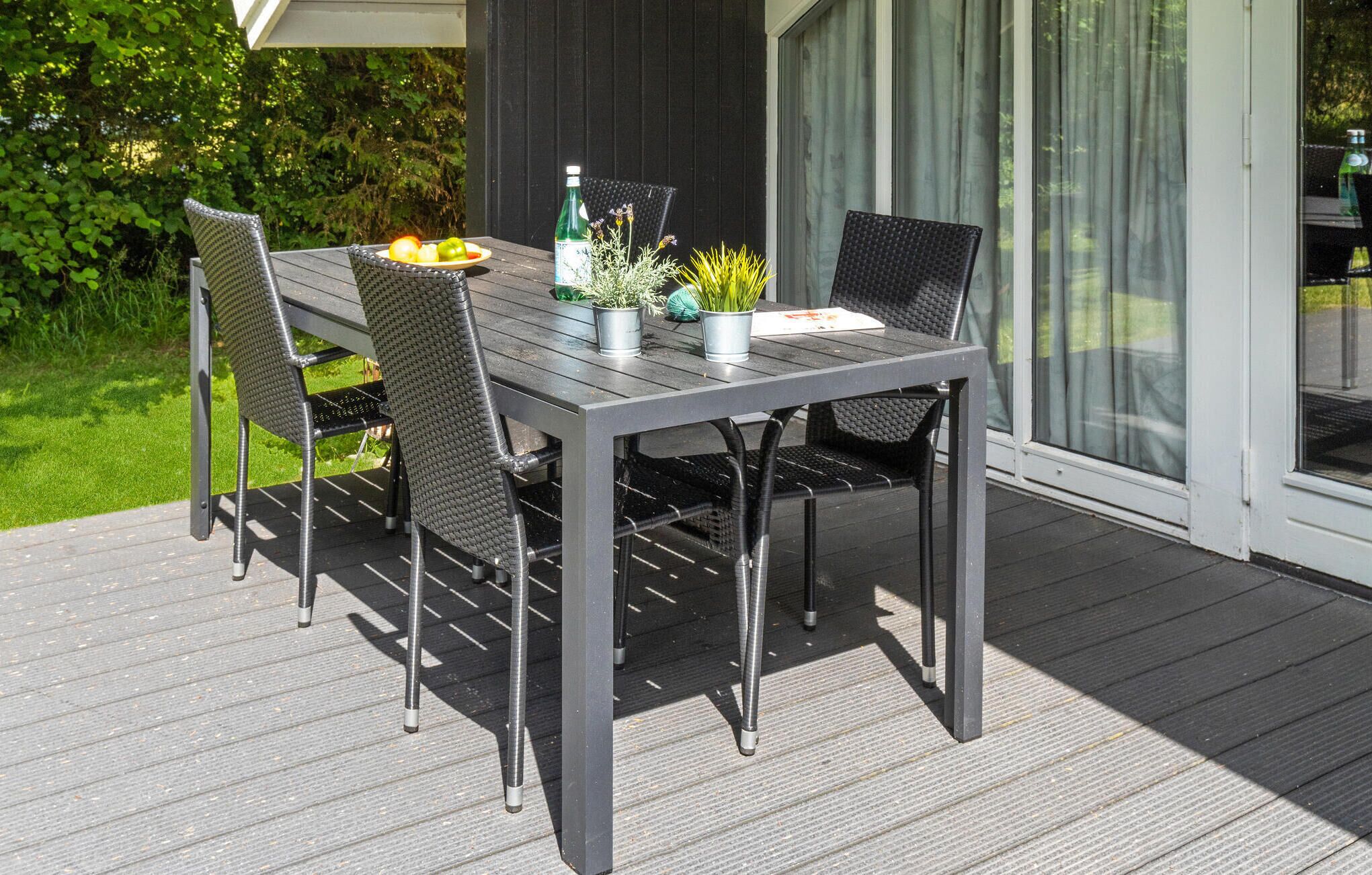 Una mesa de patio con cuatro sillas, una botella de agua y plantas en macetas.