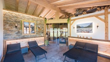 Un espacio de descanso acogedor con paredes de piedra, vigas de madera y chimenea.