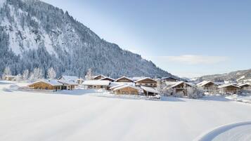 Un pueblo cubierto de nieve con chalets de madera, cielo despejado y una pista de esquí.