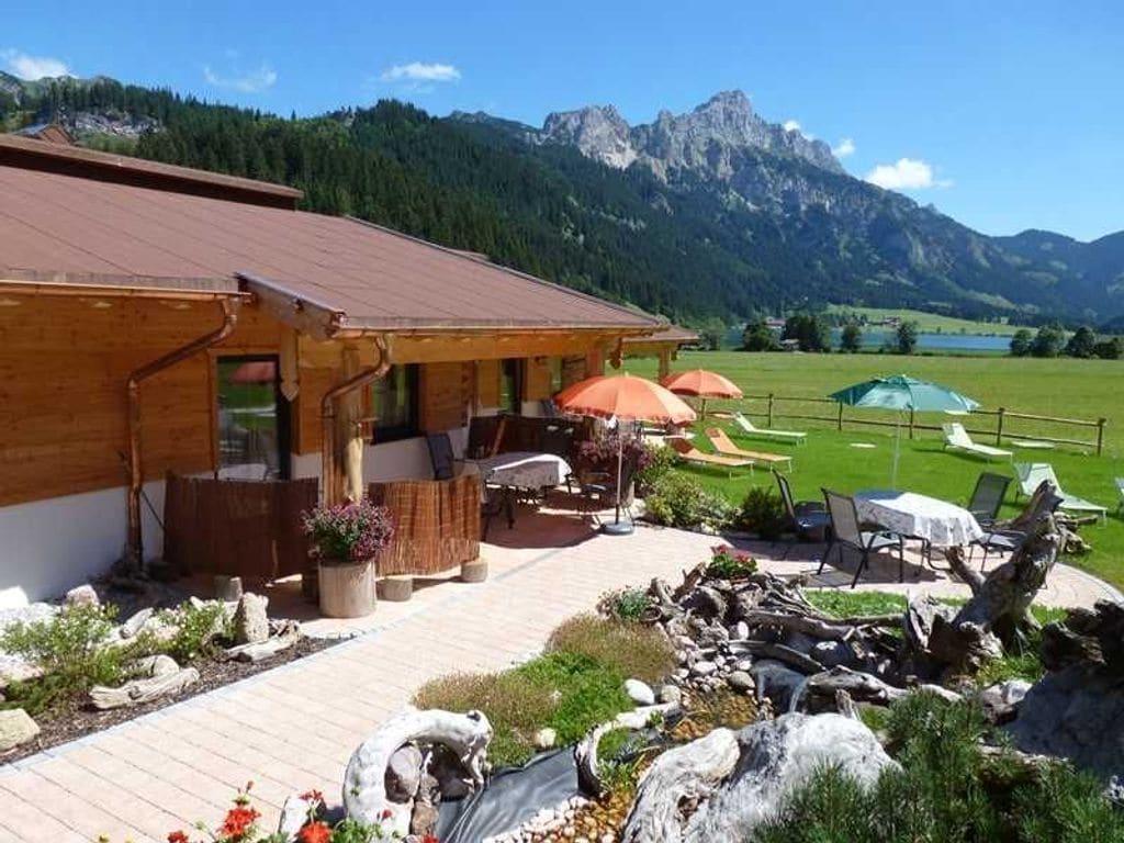 Un bâtiment en bois doté d’une terrasse et offrant une vue sur les montagnes.