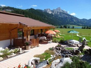 A wooden building with outdoor seating and a view of mountains.