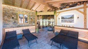 A cozy lounge area with stone walls, wooden beams, and a fireplace. - Chalet Holiday House 12 - Almdorf Tirol (Haldensee)