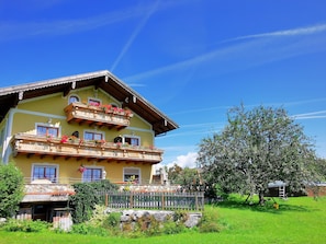 A multi-story building with balconies, a stone facade, and a surrounding garden. - Sunnhof - Arnika vacation apartment (Gegend)