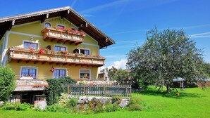 A multi-story building with balconies, a stone facade, and a surrounding garden. - Sunnhof - Arnika vacation apartment (Gegend)