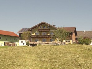 A large two-story house with a balcony, solar panels, and a red roof.