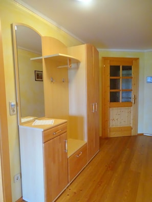 A room with a wooden wardrobe, a mirror, and a door with glass panels.