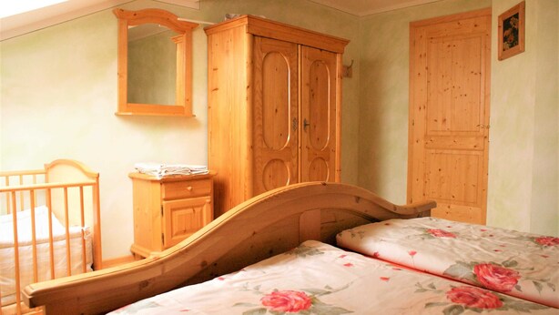 A bedroom with a wooden bed, a wooden wardrobe, and a wooden dresser. - Sunnhof - Arnika vacation apartment (Gegend)