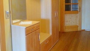 A room with a wooden wardrobe, a mirror, and a door with glass panels. - Sunnhof - Arnika vacation apartment (Gegend)
