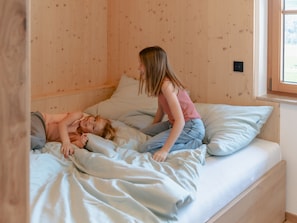 A wooden-paneled room with a bed, pillows, and a window.