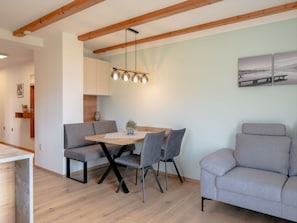 Ein Essbereich mit einem Holztisch, grauen Stühlen und einer hängenden Leuchte.