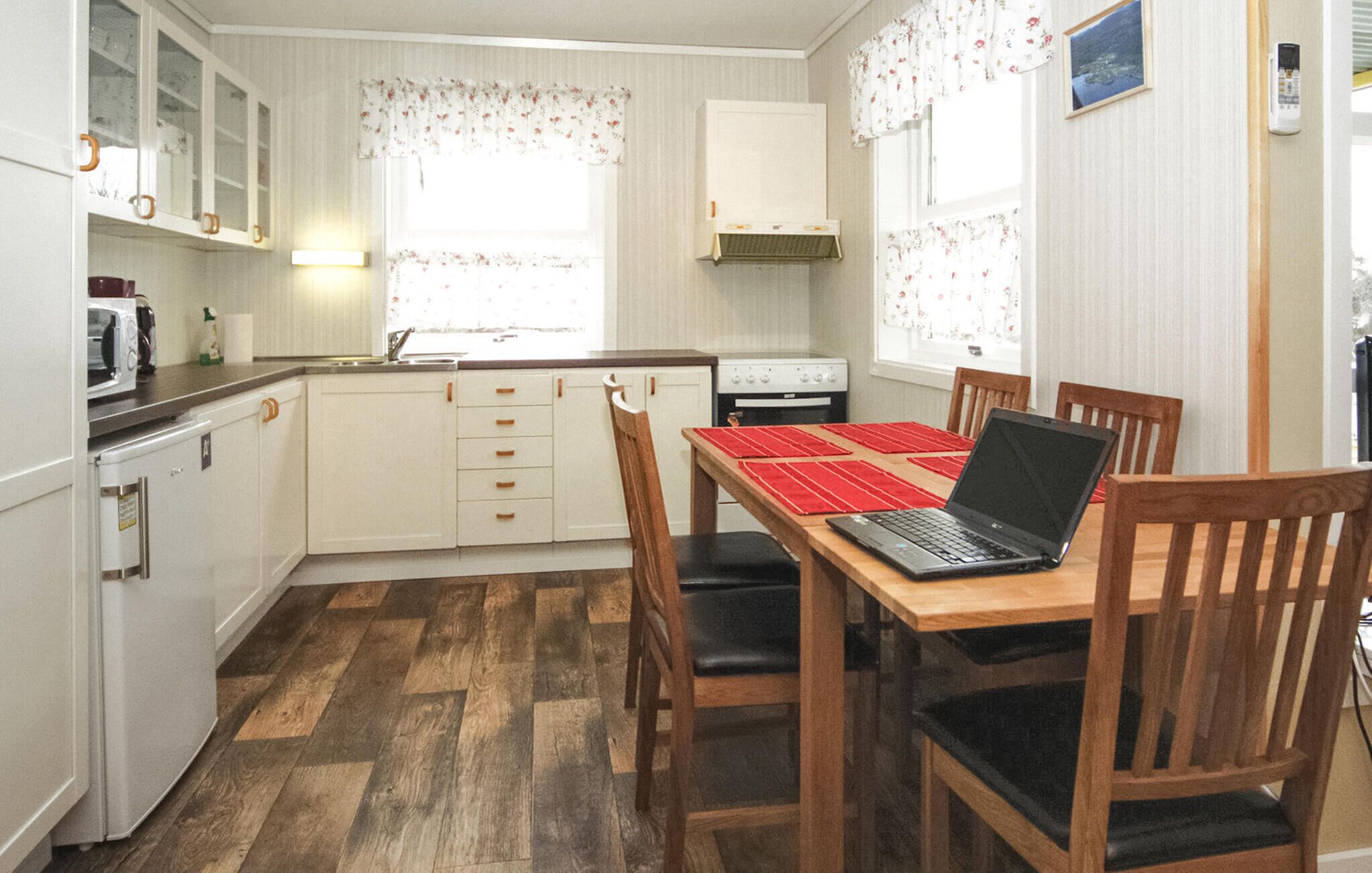 A compact kitchen with white cabinets, a stove, a microwave, and a dining table with chairs.