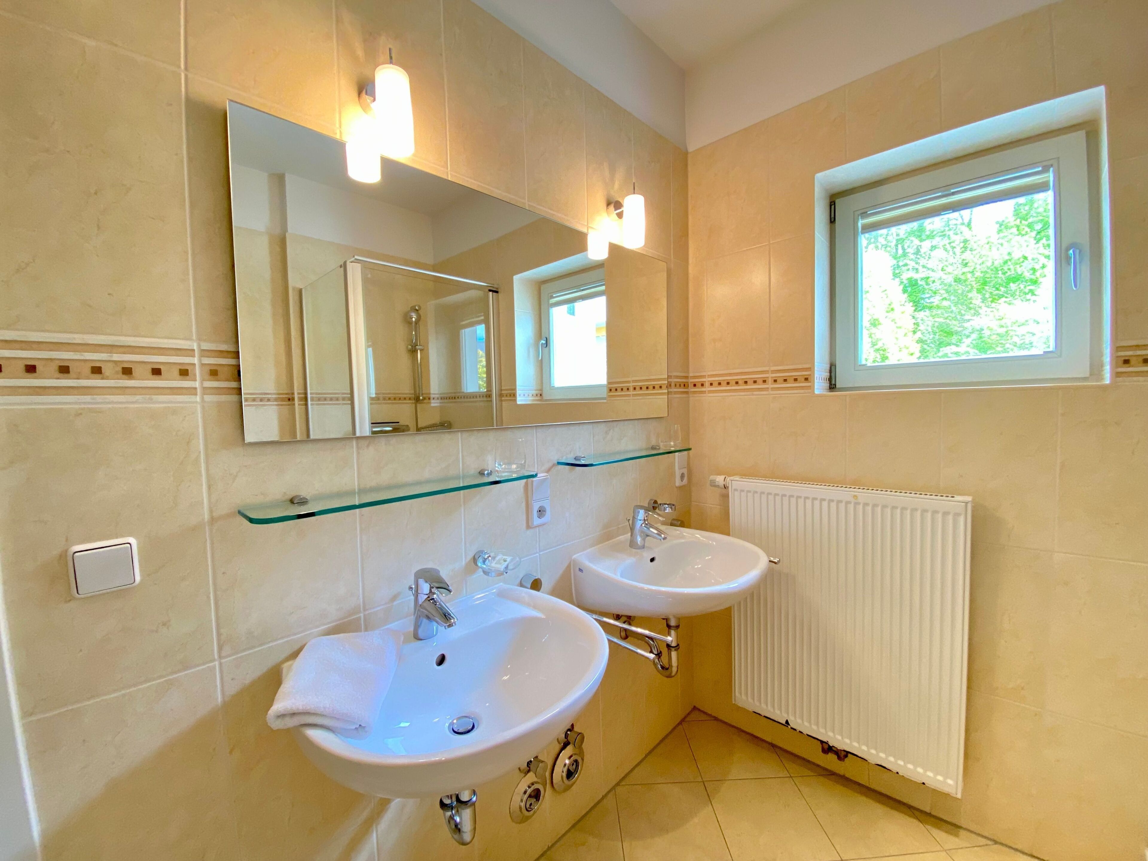 A bathroom with two sinks, a mirror, and a window.