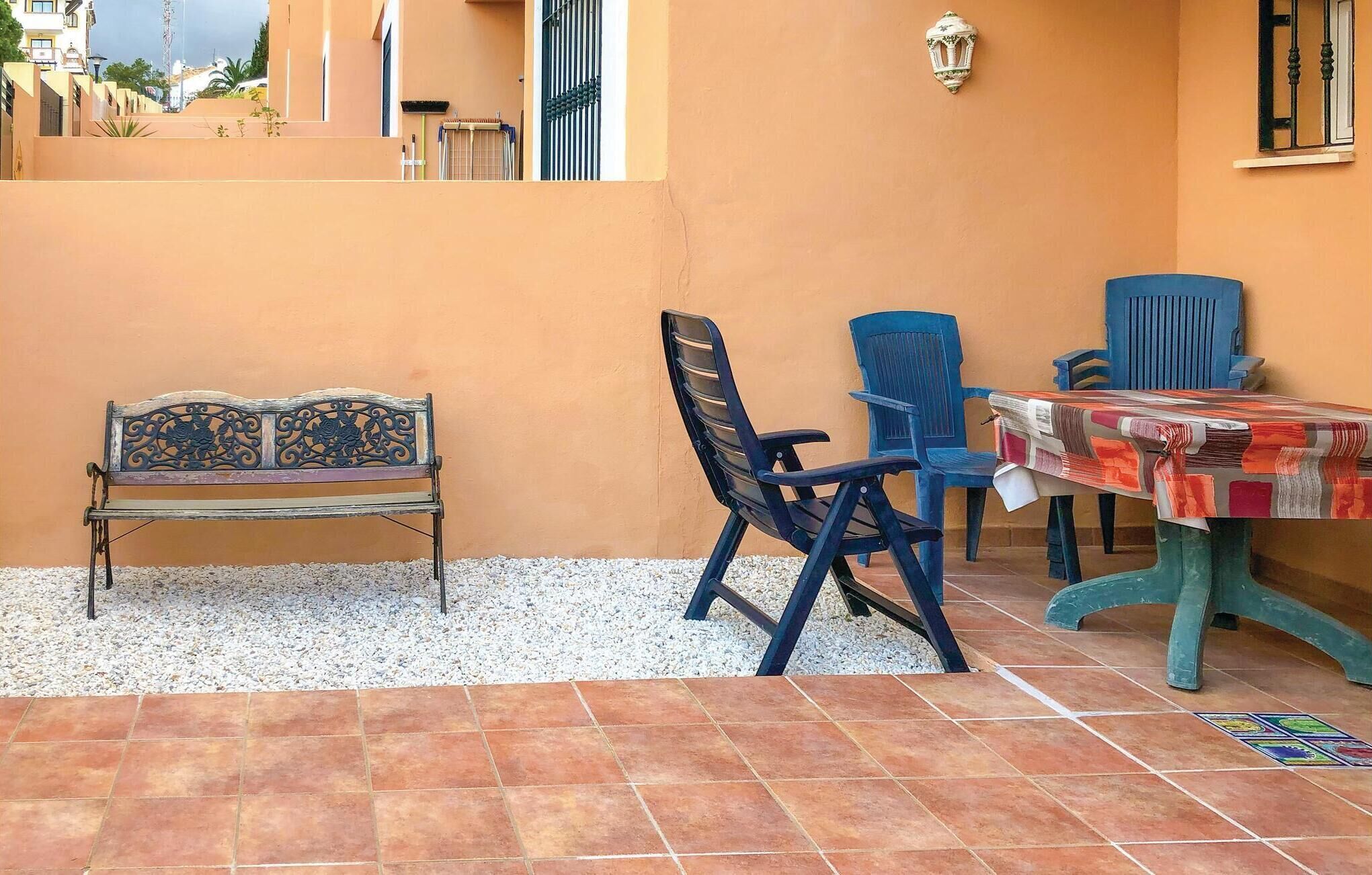 Une terrasse avec un banc, deux chaises et une table sur laquelle sont posés des journaux.