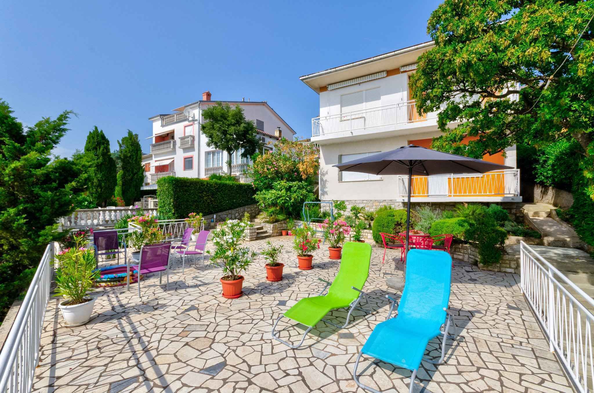 A courtyard with stone flooring, potted plants, and outdoor seating.